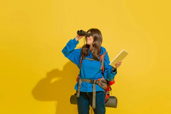 Full length portrait of a cheerful young caucasian tourist girl isolated on yellow background — Stock Photo, Image