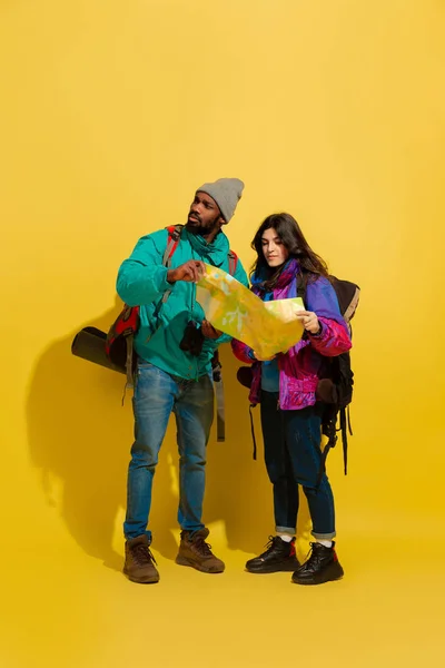 Retrato de una alegre pareja de turistas jóvenes aislados sobre fondo amarillo — Foto de Stock