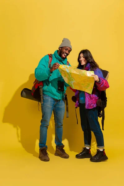 Portrait of a cheerful young tourist couple isolated on yellow background — Stock Photo, Image