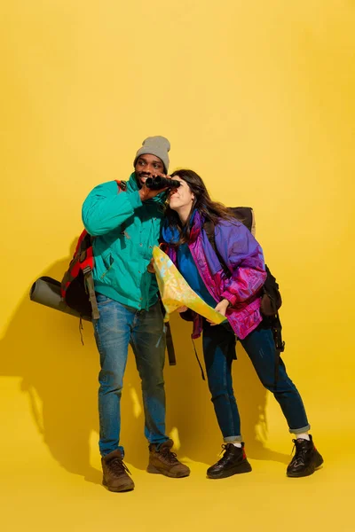 Retrato de una alegre pareja de turistas jóvenes aislados sobre fondo amarillo — Foto de Stock