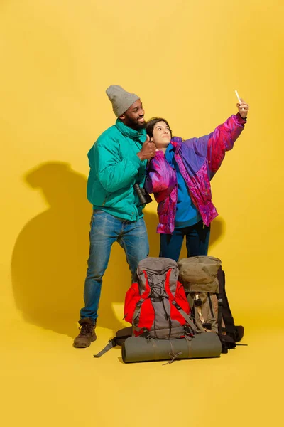 Portrait of a cheerful young tourist couple isolated on yellow background — Stock Photo, Image