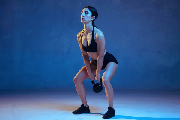 Kaukasische jonge vrouwelijke atleet oefenen op blauwe studio achtergrond in neon licht — Stockfoto