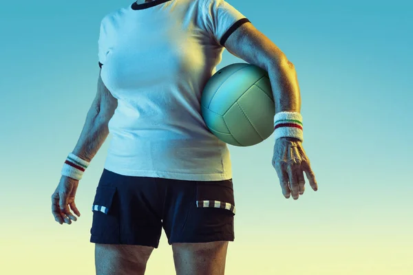 Seniorin beim Volleyballtraining in Sportbekleidung auf Steigungshintergrund in Neonlicht — Stockfoto