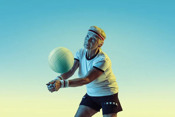 Seniorin beim Volleyballtraining in Sportbekleidung auf Steigungshintergrund in Neonlicht — Stockfoto