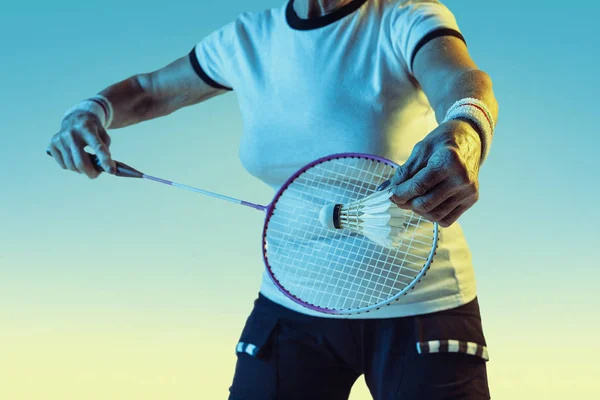 Seniorin spielt Badminton in Sportbekleidung auf Steigungsuntergrund im Neonlicht — Stockfoto