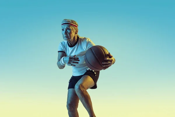 Senior kvinna spelar basket i sportkläder på lutning bakgrund i neon ljus — Stockfoto