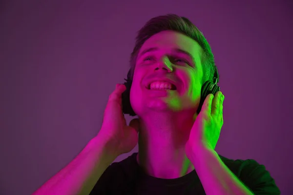 Caucasian mans portrait isolated on purple studio background in neon light — Stock Photo, Image