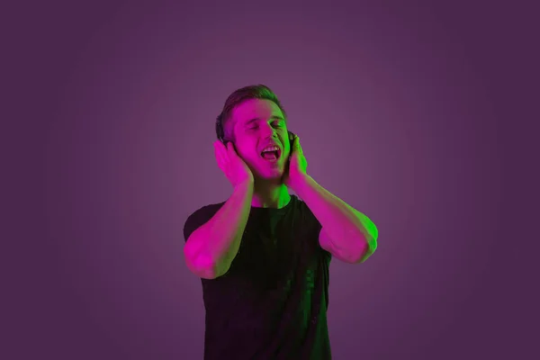 Portret caucazian mans izolat pe fundal studio violet în lumină neon — Fotografie, imagine de stoc