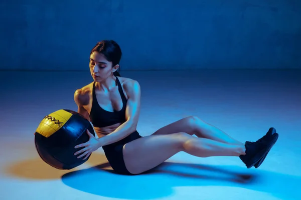 Caucasian young female athlete practicing on blue studio background in neon light — 스톡 사진