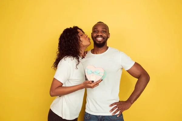 Valentines day celebration, happy african-american couple isolated on yellow background