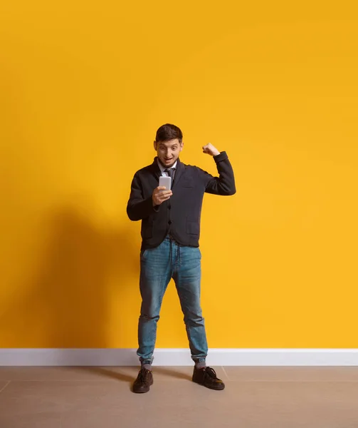 Young caucasian man using smartphone. Full body length portrait isolated over yellow background. — 스톡 사진