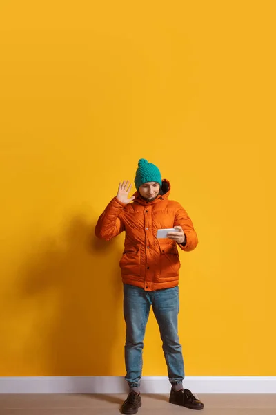 Joven hombre caucásico usando smartphone. Retrato de cuerpo entero aislado sobre fondo amarillo . — Foto de Stock