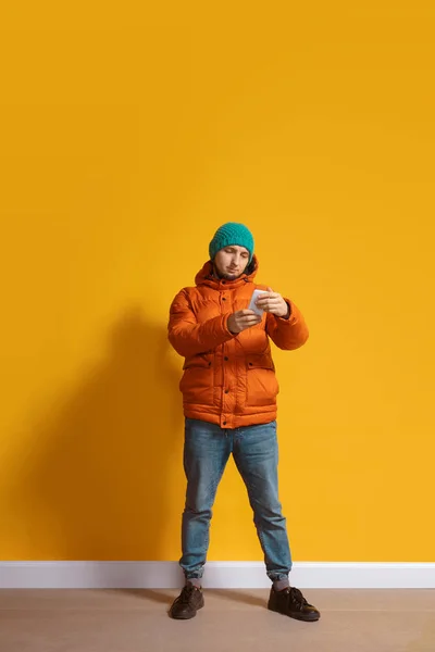 Een jonge blanke man die een smartphone gebruikt. Volledige lichaamslengte portret geïsoleerd over gele achtergrond. — Stockfoto