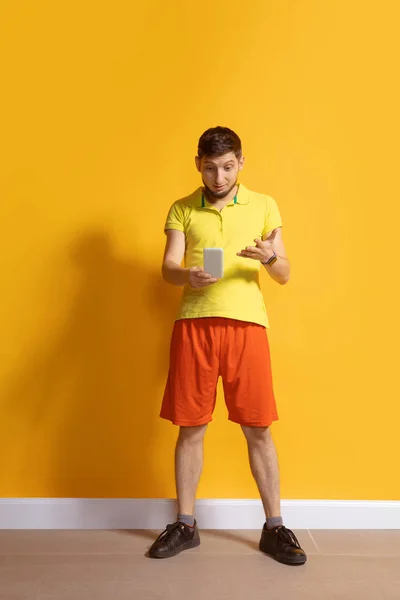 Homem caucasiano jovem usando smartphone. Retrato de corpo inteiro isolado sobre fundo amarelo . — Fotografia de Stock