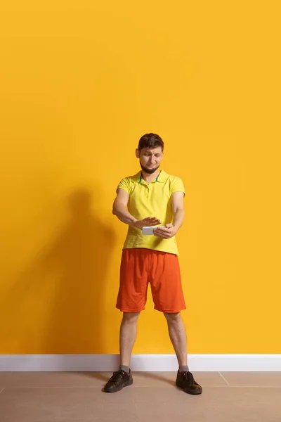 Young caucasian man using smartphone. Full body length portrait isolated over yellow background. — 스톡 사진