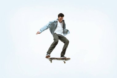 Kafkasyalı genç kaykaycı beyaz bir arka planda tek başına at sürüyor.