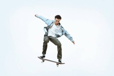 Kafkasyalı genç kaykaycı beyaz bir arka planda tek başına at sürüyor.