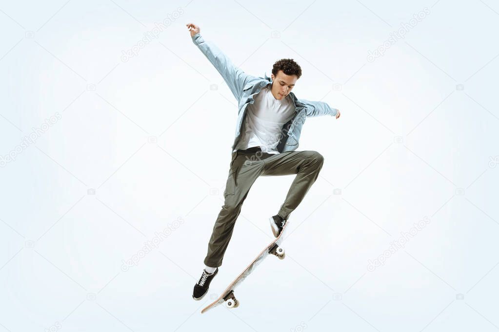 Caucasian young skateboarder riding isolated on a white background