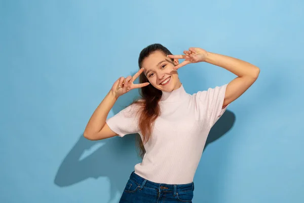 Портрет белой девушки-подростка на фоне синей студии — стоковое фото