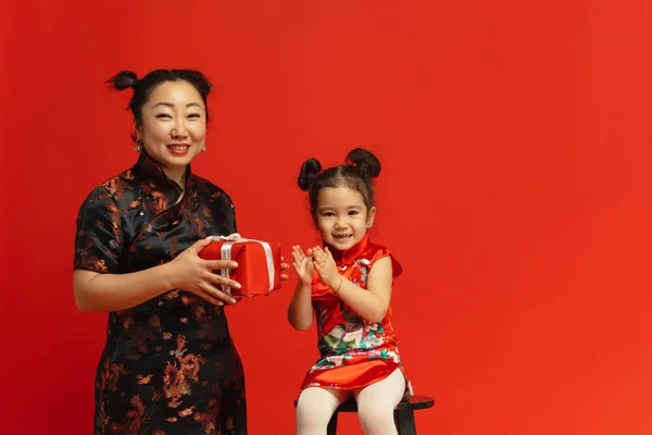 Feliz Año Nuevo Chino. Madre asiática e hija retrato aislado sobre fondo rojo — Foto de Stock