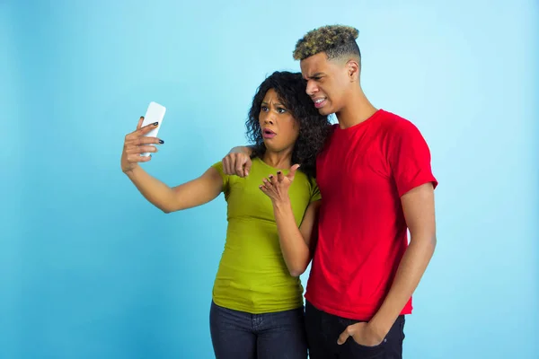 Jeune homme et femme afro-américain émotionnel sur fond bleu — Photo