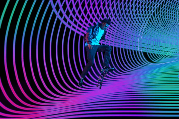 Kaukasische junge Skateboarder Reiten auf dunklen neonbeleuchteten Linie Hintergrund — Stockfoto