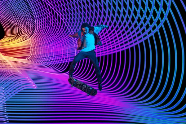 Kaukasische jonge skateboarder rijden op donkere neon verlichte lijn achtergrond — Stockfoto