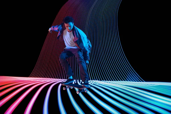 Caucasico giovane skateboarder equitazione su scuro neon illuminato linea di sfondo — Foto Stock