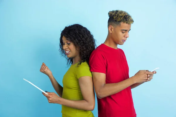 Jeune homme et femme afro-américain émotionnel sur fond bleu — Photo