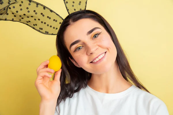 Easter bunny woman with bright emotions on yellow studio background