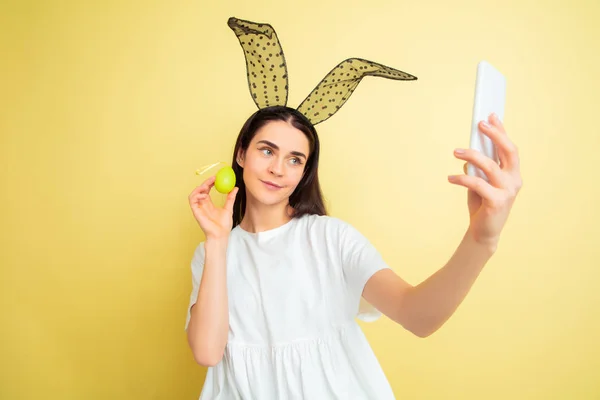 Easter bunny woman with bright emotions on yellow studio background