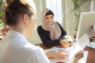 Portrait of a beautiful arabian businesswoman wearing hijab while working clipart