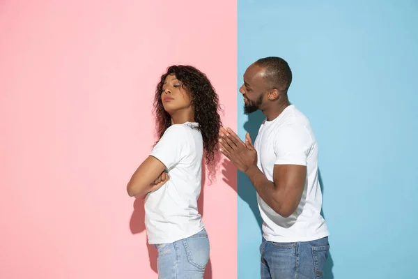 Jeune homme et femme émotionnelle sur fond rose et bleu — Photo