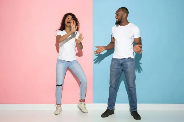 Jonge emotionele man en vrouw op roze en blauwe achtergrond — Stockfoto