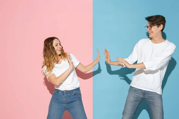 Jonge emotionele man en vrouw op roze en blauwe achtergrond — Stockfoto