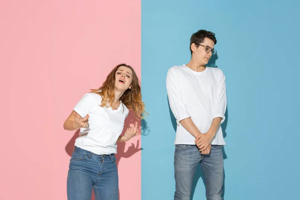 Jeune homme et femme émotionnelle sur fond rose et bleu — Photo