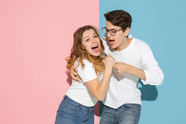 Jovem homem emocional e mulher no fundo rosa e azul — Fotografia de Stock