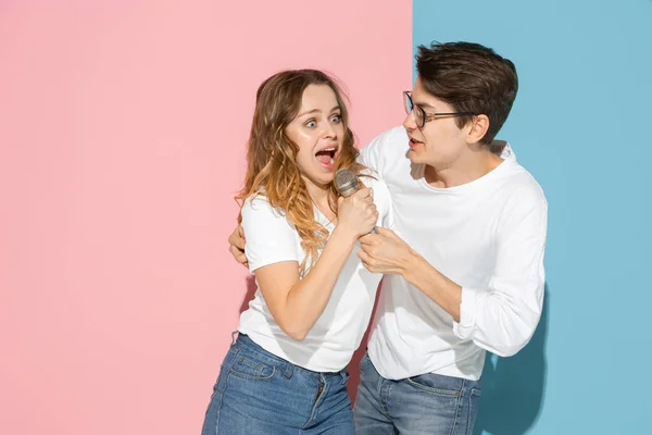 Jovem homem emocional e mulher no fundo rosa e azul — Fotografia de Stock