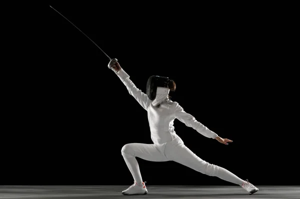 Tiener meisje in schermen kostuum met zwaard in de hand geïsoleerd op zwarte achtergrond — Stockfoto