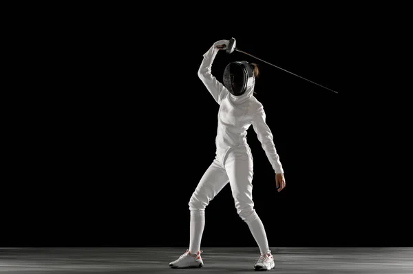 Девушка-фехтовальщица в костюме с мечом в руке на черном фоне — стоковое фото