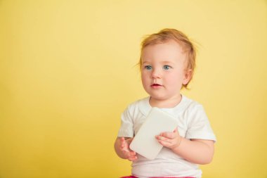 Kafkasyalı küçük kız, sarı stüdyo arka planında izole edilmiş çocuklar.