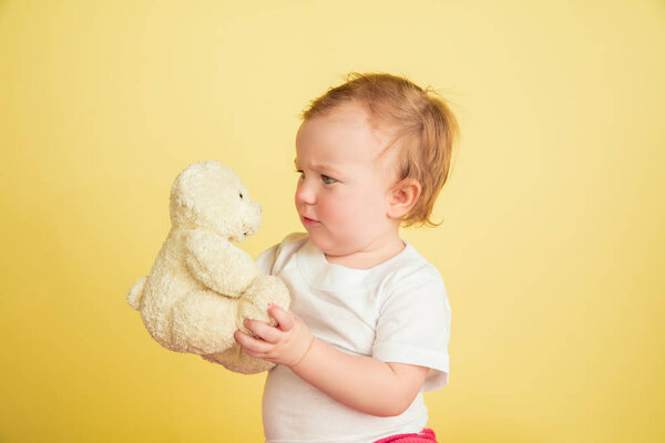 Caucasian little girl, children isolated on yellow studio background