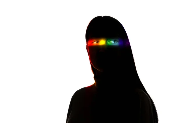 Dramatiskt porträtt av en flicka i mörkret på vit studio bakgrund med regnbåge färgade linje — Stockfoto