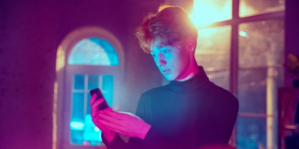 Filmový portrét pohledného mladého muže v neonově osvětleném interiéru — Stock fotografie