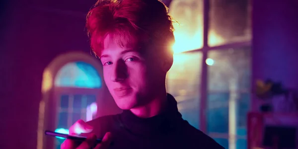 Filmový portrét pohledného mladého muže v neonově osvětleném interiéru — Stock fotografie