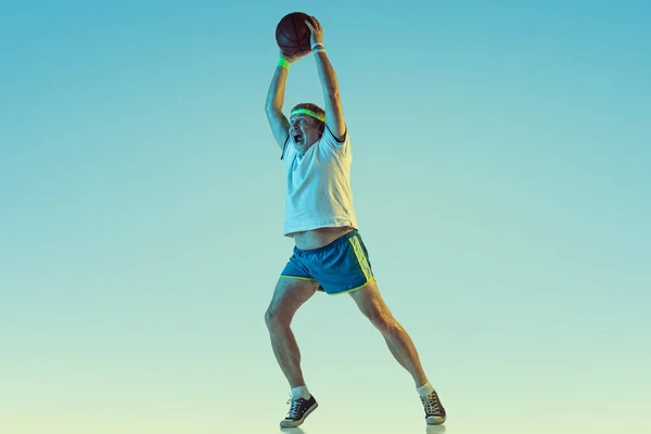 Senior-Mann spielt Basketball in Sportbekleidung auf Gradientenhintergrund und Neonlicht — Stockfoto