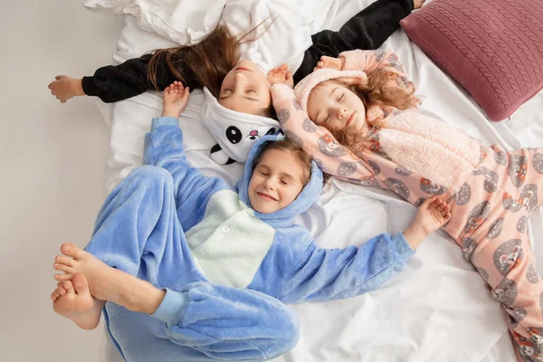 Children in soft warm pajamas having party colored bright playing at home — ストック写真