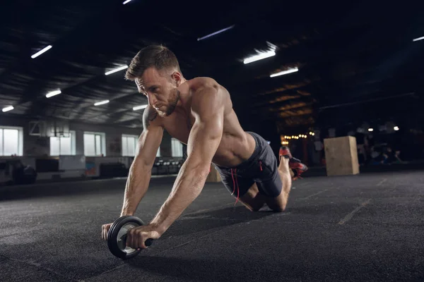 Joven atleta masculino sano haciendo ejercicios en el gimnasio — Foto de Stock