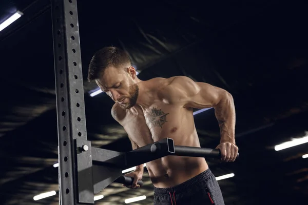 Joven atleta masculino sano haciendo ejercicios en el gimnasio —  Fotos de Stock