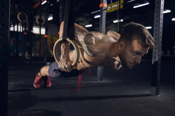 Joven atleta masculino sano haciendo ejercicios en el gimnasio — Foto de Stock